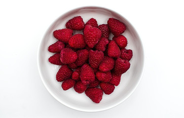 Raspberries in a white bowl, isolated on white background. Top view