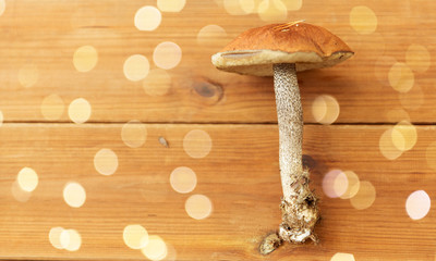 nature, environment and edible mushrooms concept - orange-cap boletus on wooden background