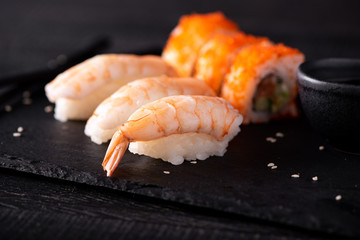 sushi with tiger shrimp and rolls on black board