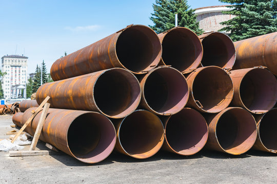 Large, old and rusty sewer pipes stacked in one batch for recycling