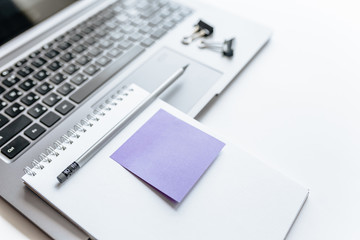 Notebook, laptop, stickers, paper clips in the workspace on the table in the office.