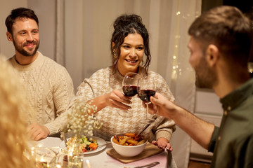 holidays, celebration and people concept - happy friends having christmas dinner at home drinking non-alcoholic red wine