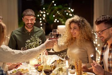 holidays, celebration and people concept - happy friends having christmas dinner party drinking non-alcoholic red wine at home