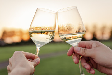 Couple cheering with wine during sunset time outside.