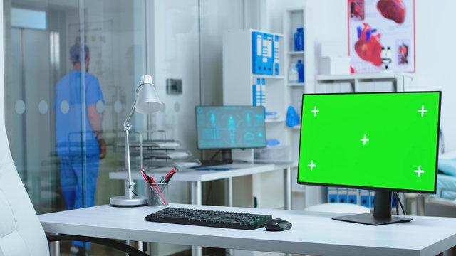 Monitor with green screen in hospital while male assistant waiting elevator. Computer with blank space available on medicine specialist in clinic cabinet.