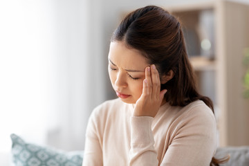 people and health problem concept - sick asian woman having headache at home