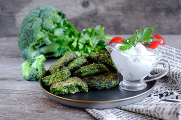 Vegetarian patties on a plate with the tomatoes. Served with sour cream sauce. Healthy vegetarian or vegan food.Lie on the cutting Board with tomato greens. dIet pancakes made from broccoli, spinach