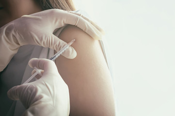 The doctor makes vaccination in the shoulder of the patient female. The concept of planned...