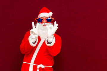 Close up joyful funny playful santa showing peace victory and zero signs, fooling around, in trendy specs, so confident.