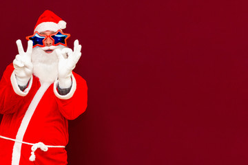 Close up joyful funny playful santa showing peace victory and zero signs, fooling around, in trendy specs, so confident.
