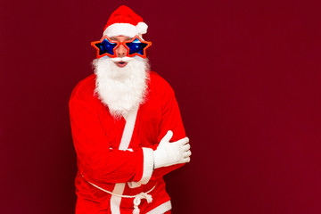 Portrait of positive young Santa look at camera red studio background with copy space cross hands on chest