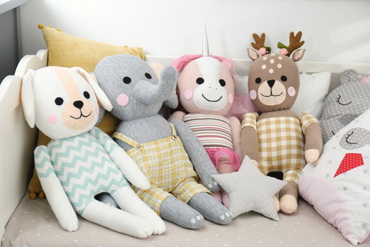 Cute toys and pillows on bed in baby room. Interior elements