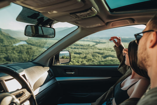 Young Couple on a Road Trip, Man Diving Car with Woman Sitting on Passenger Seat