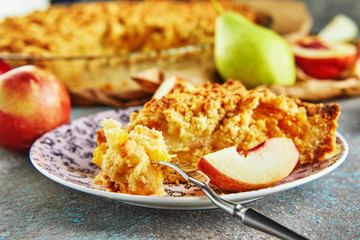 A slice of peach and pear pie on a plate and a piece chopped onto a fork
