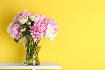 Beautiful peonies on white table against yellow background. Space for text