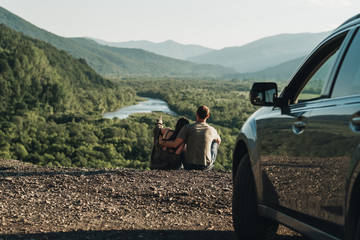 Young Traveler Couple on a Road Trip, Man and Woman Enjoying Journey on Their Car Over Beautiful Landscape