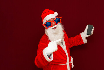 Portrait of satisfied santa claus use cell phone comment newyear posts reading news isolated over red background