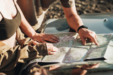Traveler Couple on a Road Trip, Man and Woman Using Map on Journey Near Their Car Over Beautiful Landscape © Romvy