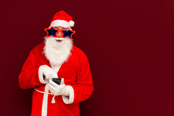 Portrait of satisfied santa claus use cell phone comment newyear posts reading news isolated over red background