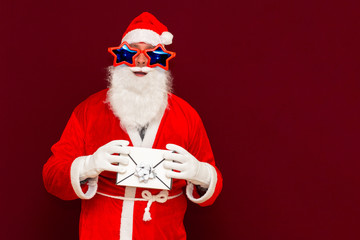 Fake Bearded man in Santa Claus hat holds gift letter envelope box. Ch hristmas gift. Christmas or New Year holidays.