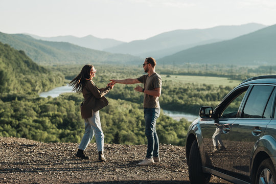 Young Traveler Couple on a Road Trip, Man and Woman Enjoying Journey on Their Car Over Beautiful Landscape