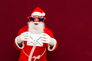Fake Bearded man in Santa Claus hat holds gift letter envelope box. Ch hristmas gift. Christmas or New Year holidays.