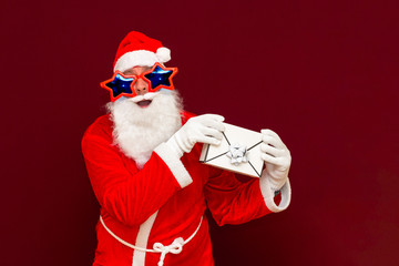 Fake Bearded man in Santa Claus hat holds gift letter envelope box. Ch hristmas gift. Christmas or New Year holidays.