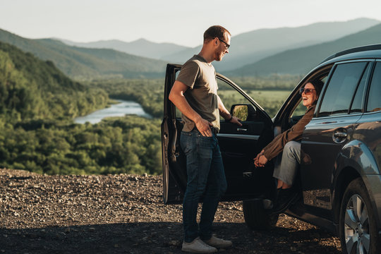 Young Traveler Couple on a Road Trip, Man and Woman Enjoying Journey on Their Car Over Beautiful Landscape