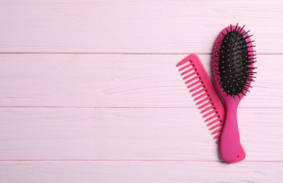 Hair brush and comb on pink wooden background, flat lay. Space for text