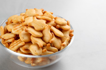 Delicious goldfish crackers in bowl on grey table, closeup