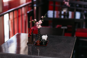 cope space in the interior and of restaurant in dark colors, flowers in Asian style are on the table