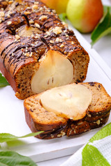 Sliced chocolate cake with pears on white cutting board