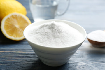 Baking soda in bowl on blue wooden table