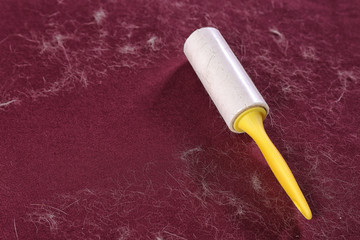 Lint roller on red fabric covered with hair. Space for text