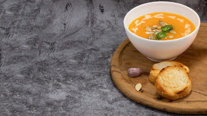 Pumpkin cream soup with seeds on a stone background, with copy space
