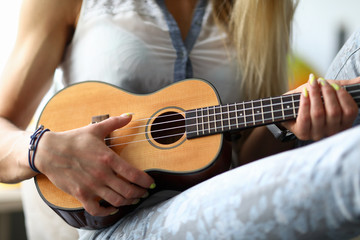 Fototapeta premium Female hands holding ukulele guitar learning how to play