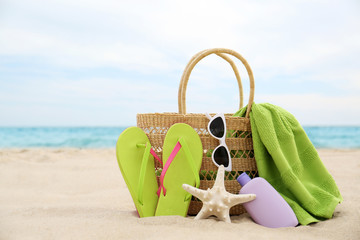 Different stylish beach objects and starfish on sand near sea