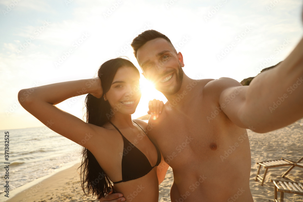 Canvas Prints Happy young couple taking selfie on beach at sunset