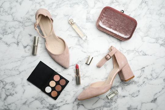 Flat lay composition with stylish shoes, cosmetics and woman's bag on white marble table