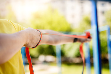 Fototapeta premium Man exercising with resistance rubber band in street, close up