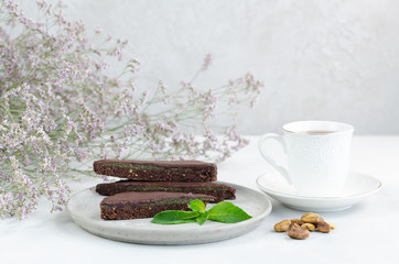 Pieces of chocolate tart with nuts and mint on a concrete plate on a white background. Close-up