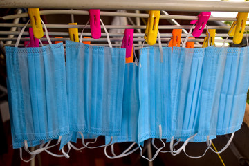 Corona Virus pandemic masks being hanged on a cloth rod after cleaning. Reusable blue colored face masks