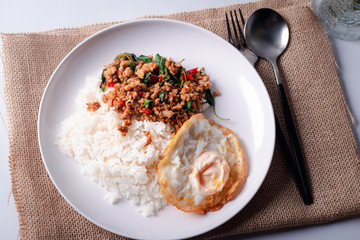 Pork basil with fried egg in a white plate on a white background.