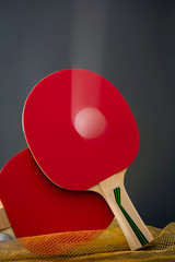 Table tennis rackets with a ball in movement in a studio shot.
