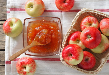 Top view.Autumn still life with apples. Apple jam surrounded by apples on a napkin on a wooden background