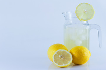 Lemon juice with ice in a glass jug Decorated with lemon slices With lemon cubes cut in half On a white backdrop