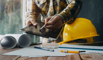 Two colleagues discussing data working and tablet, laptop with on on architectural project at construction site at desk in office