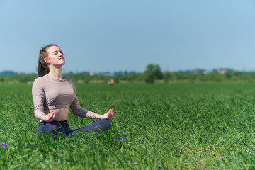 A young Caucasian girl practices yoga meditation in the fresh air. The concept of peace of mind.
