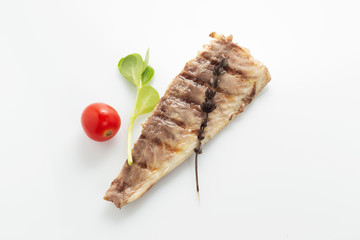 Fish fried on the grill and served on a plate with fresh vegetables
