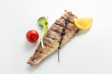 Fish fried on the grill and served on a plate with fresh vegetables